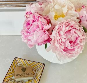 Soap dish featuring the Wayback logo and a vase of pink peonies.