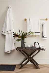 A bathroom wall with a bathrobe and two black and white bath towels hanging up.