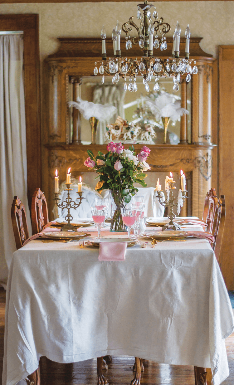 crystal chandelier hanging over a romantically set table adorned with fresh flowers and candelabras