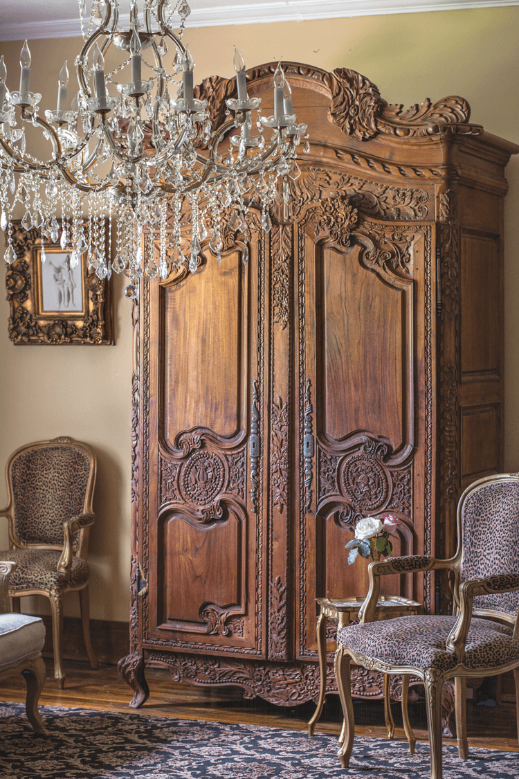 Craigslist antique, handcrafted antique armoire placed next to regal animal print arm chairs