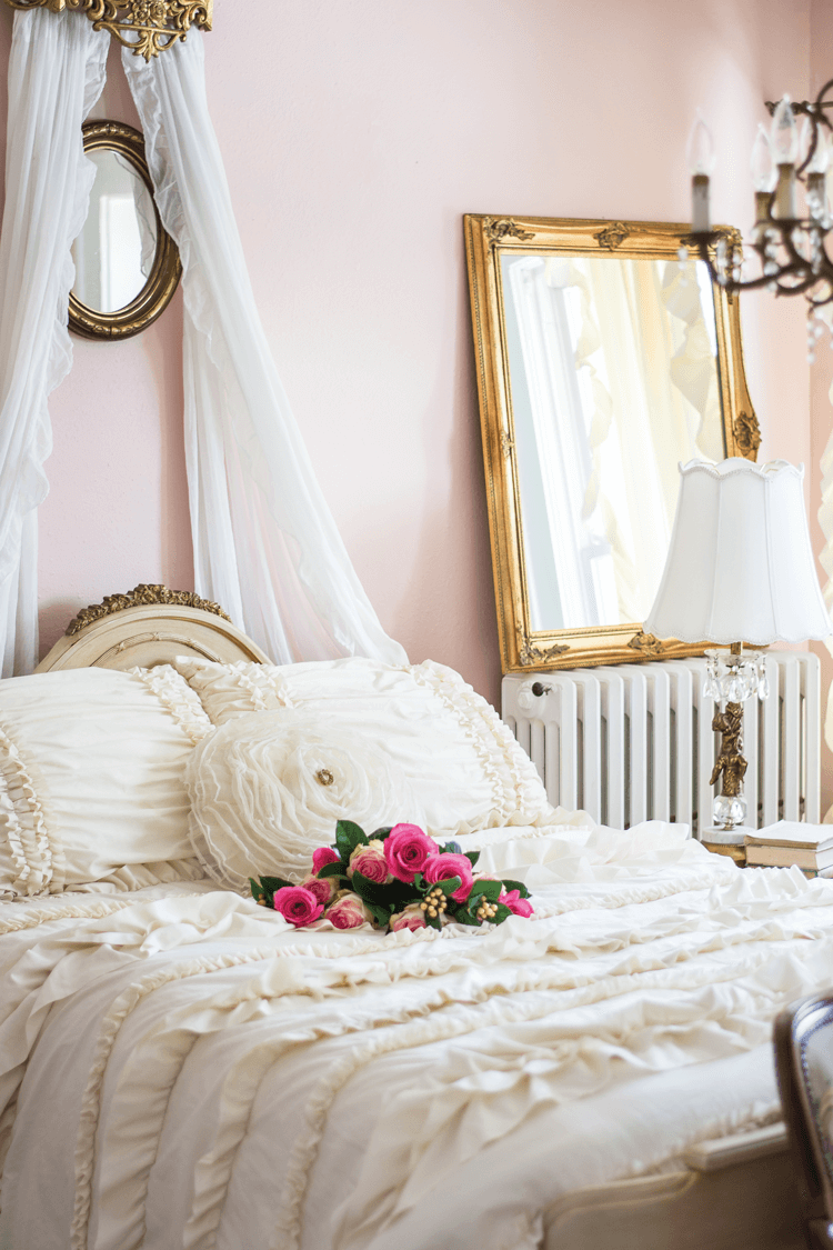 blush pink guest bedroom with cream colored romantic bedding and gold accents