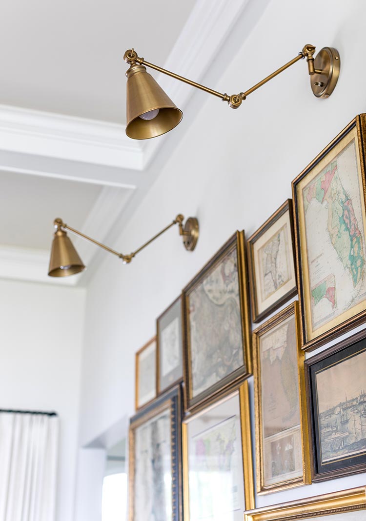 A gallery wall of vintage maps with brass wall sconces 