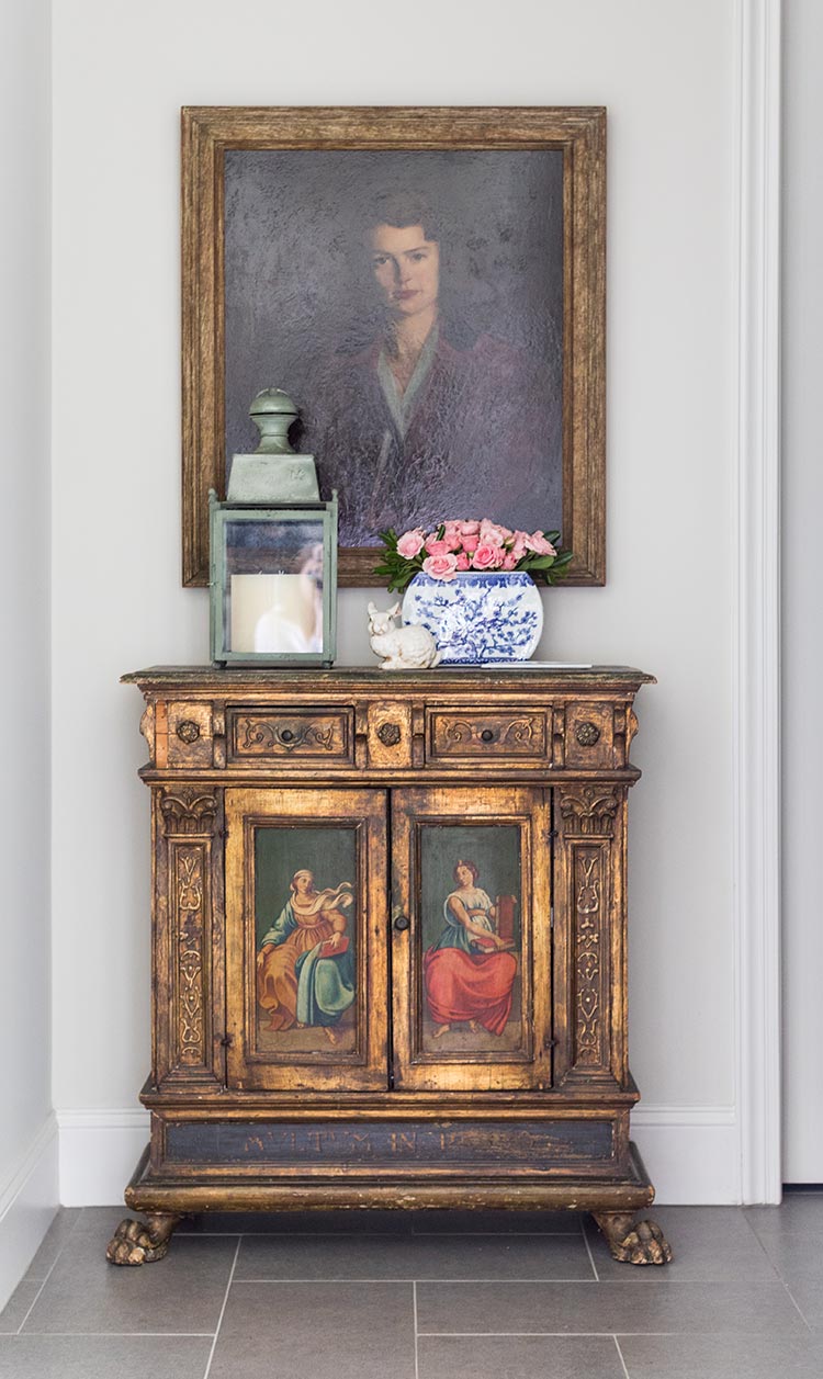 A vintage portrait hanging over a gold cabinet