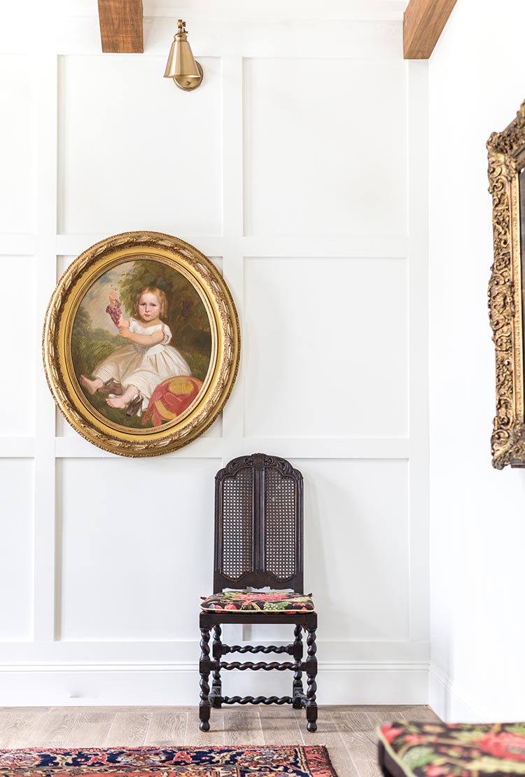 Oval classical painting of child in ornate gold frame on paneled wall.