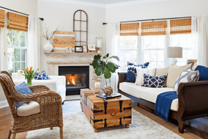 Spacious living room with light gray/beige walls, wicker and wooden rustic furniture accent pieces and pops of blue in pillows and throws.