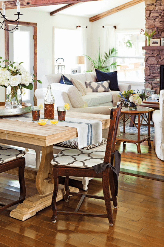 A view from the kitchen looking over the farmhouse trellis table and into the large room addition with a vaulted ceiling and freshly installed stone fireplace. 