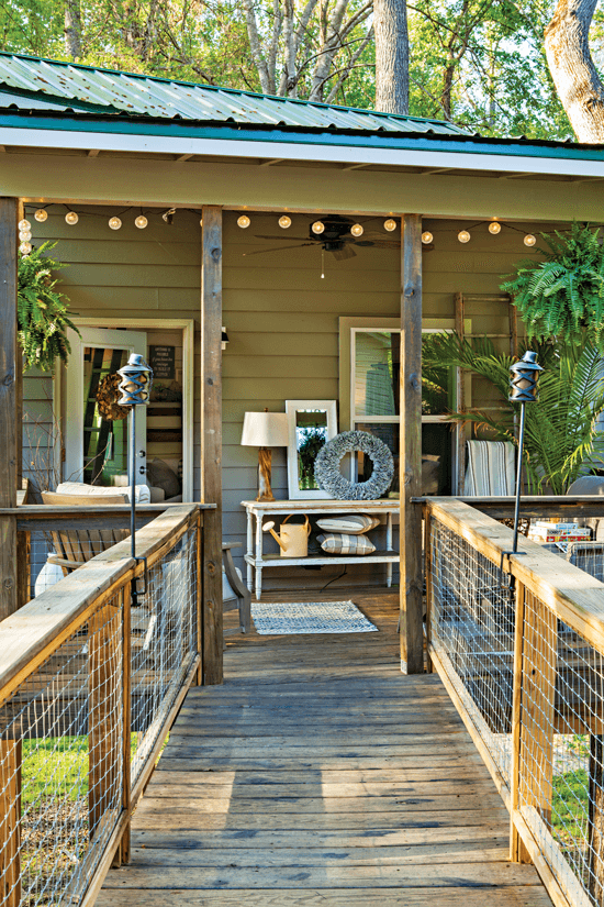 A view from the walkway up to the porch of the Tree house, featuring it's porch decor and string lighting. 