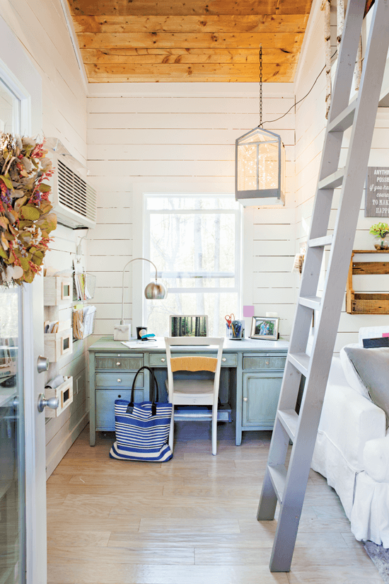 A view inside the treehouse, a tall gray ladder leads up to a hideout for the kids and straight back a small but useful desk area.