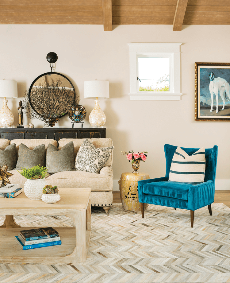 Beach farmhouse decor in the great room featuring herringbone rug, blue chair with pillow, white couch, wooden coffee table and Douglas fir ceiling