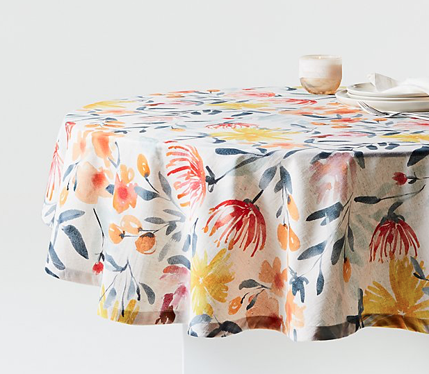 Floral linen table cloth draped over a round dining table. 