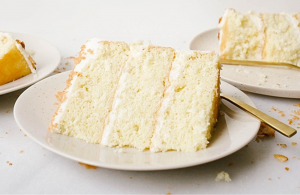 plates laid out each with a slice of three layered yellow cake with gold forks.