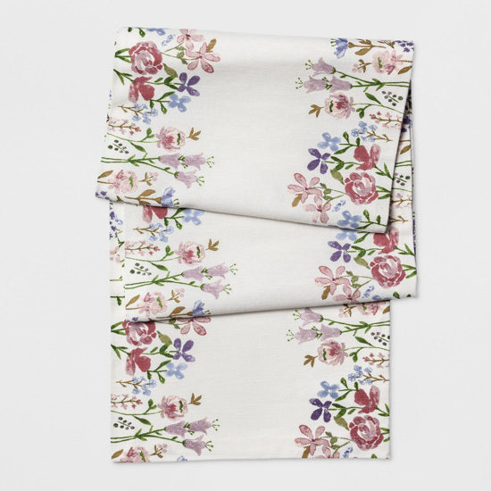 Cream colored table runner with flowers on the outside edges in shades of pink, blue and purple.