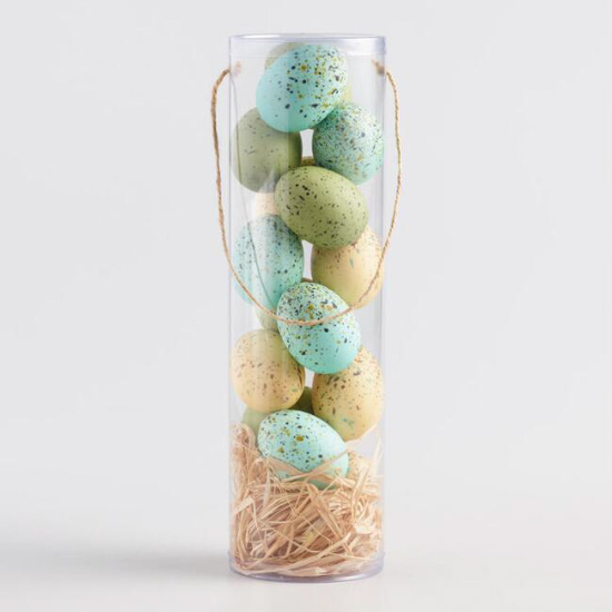 Plastic tube with twine at the bottom and pastel colored speckled eggs stacked inside. 