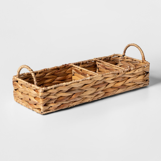 Natural thatched basket with dividers for bathroom storage.