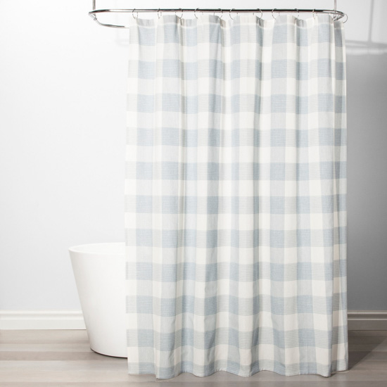 white bath tub featuring light blue and white gingham shower curtain. 