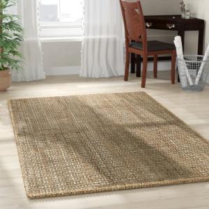 Handwoven natural colored area rug laid out on floor.
