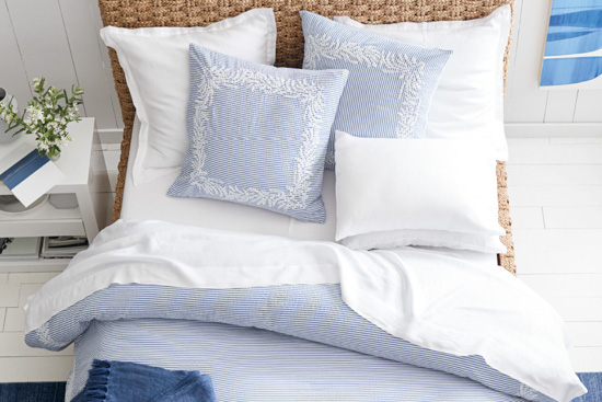 Light blue and white detailed duvet cover and pillow set displayed on a bed.