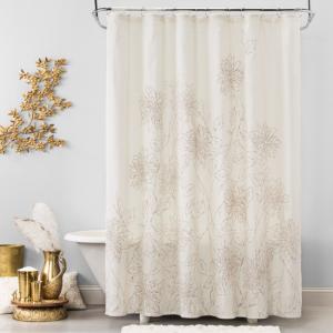 White shower curtain with gold sketched flowers on it. Bathroom scene with white tub and gold accents.