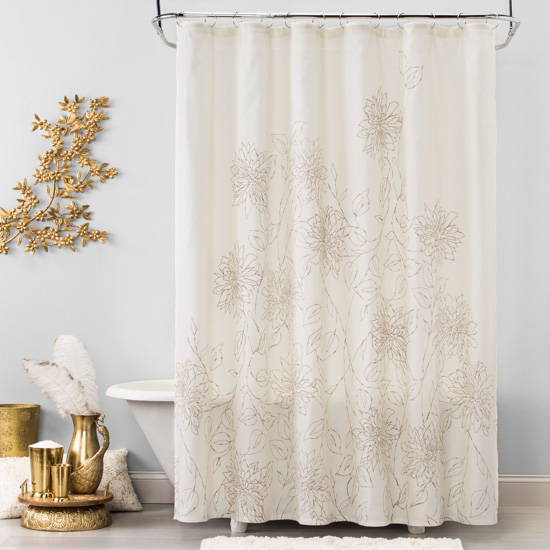 White shower curtain with gold sketched flowers on it. Bathroom scene with white tub and gold accents.