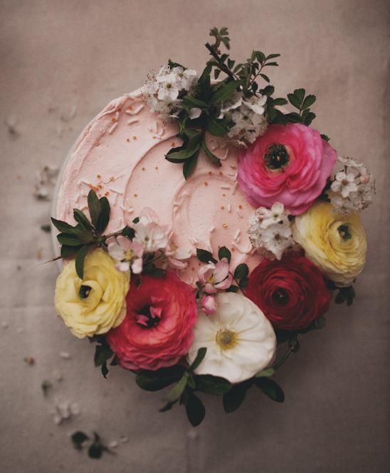 Arial view of a lovely pink frosted cake covered fresh ranunculus. 