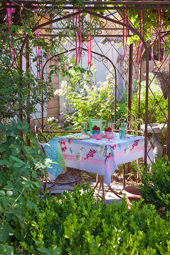 A simple gathering in the iron pergola feels extra special thanks to vintage styling and the lush layers of plantings that Jeri created to surround the space.