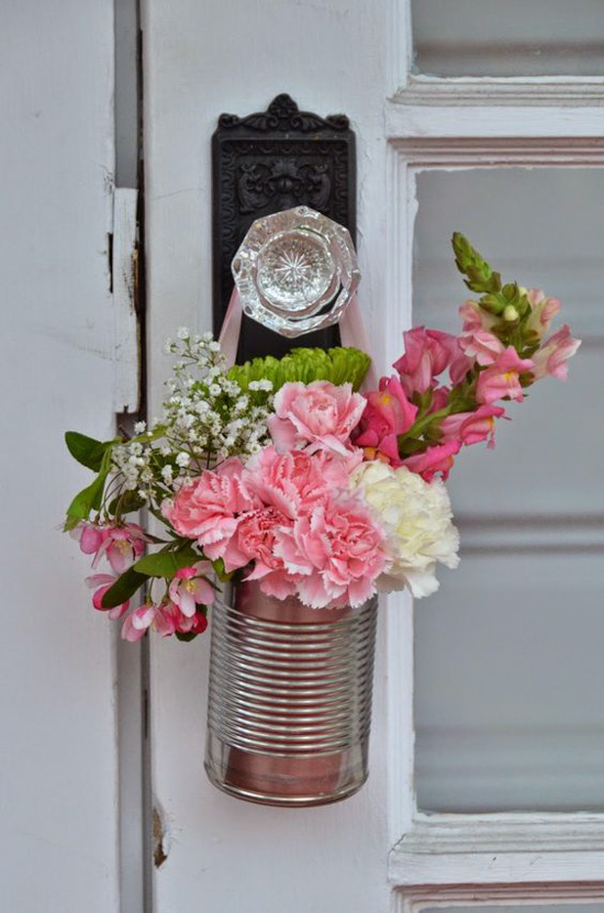 Fresh flowers in a tin can, hanging from an antique crystal doorknob. 