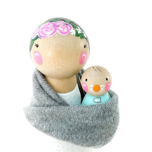 Hand painted wooden peg dolls of a mother holding a baby in a sling.