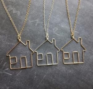 Three examples of bent metal house outlines on necklace chains.