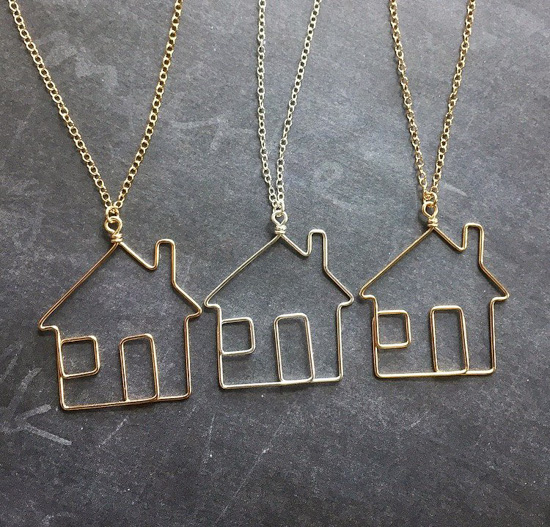 Three examples of bent metal house outlines on necklace chains. 