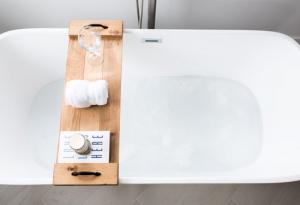 white bathtub with a wooden hand-crafted bath caddy