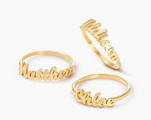 Three individual gold rings with cursive names on them.