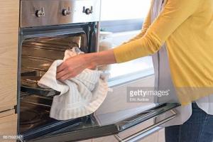 A woman taking the rack out of an oven.