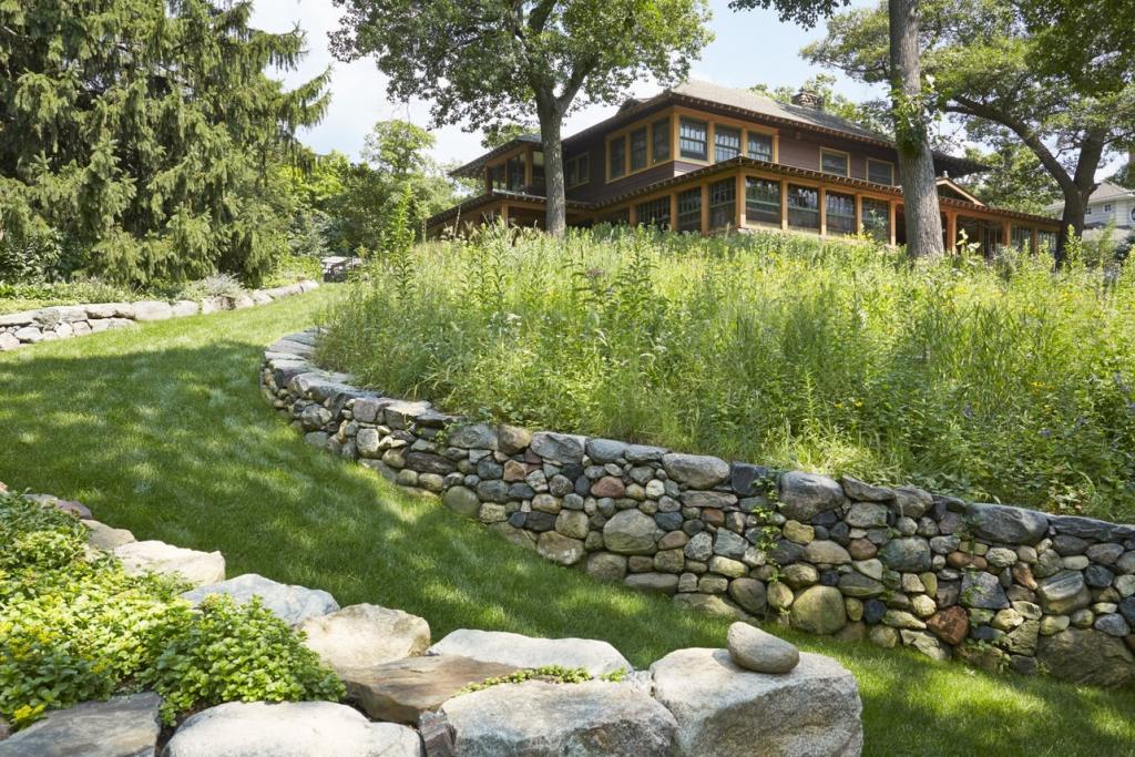 A Craftsman-style home with a grassy meadow in front of it.