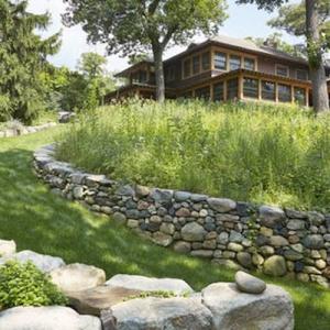 A Craftsman-style home with a grassy meadow in front of it.