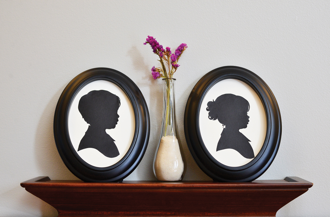 Custom oval framed silhouette images placed together on a shelf with a vase in-between them. 