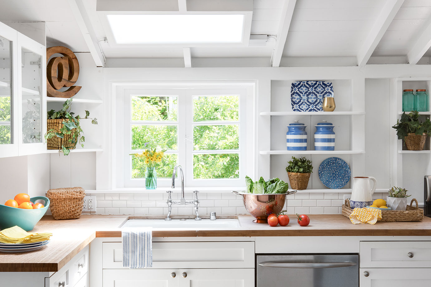 bright white kitchen with blue accents and wooden countertops. 