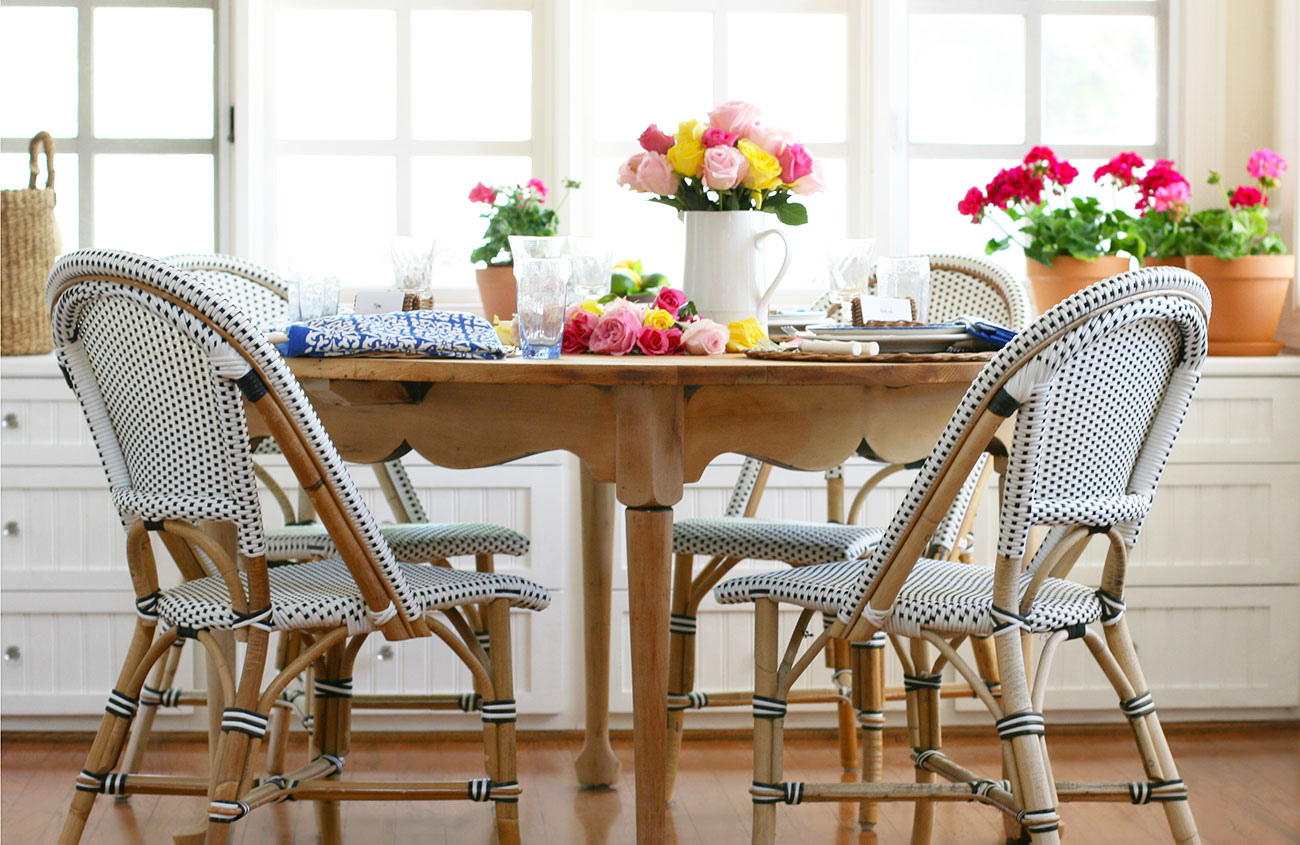 garden inspired french country table with roses, geraniums, lemons, wicker bistro chairs, roses, geramiums and rattan chargers