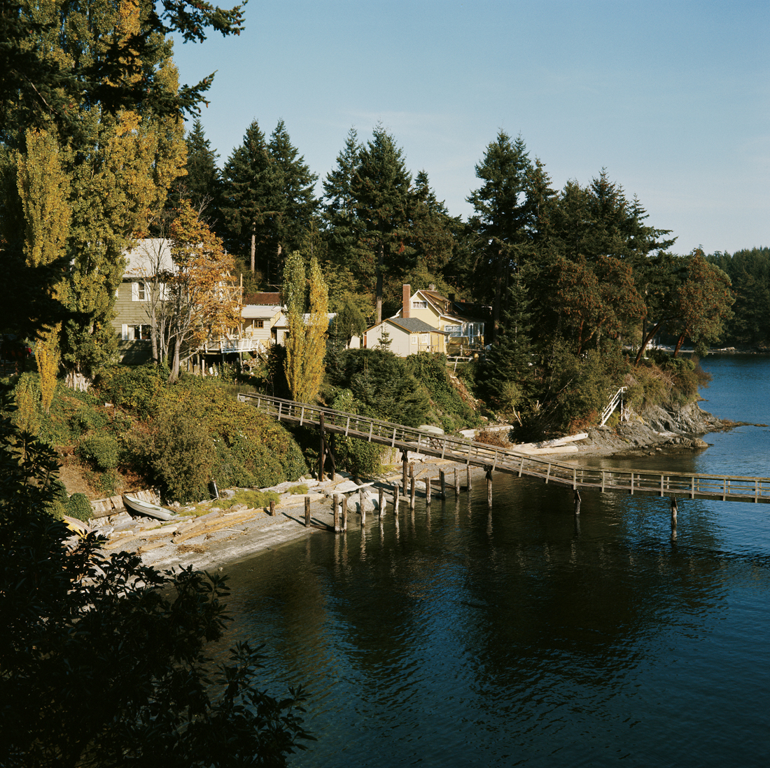 A sleepy cottage town over looking the water and a long dock. 