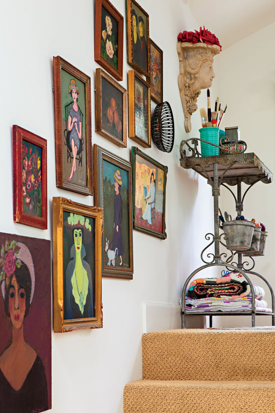 A collection of vintage portrait paintings up a staircase wall