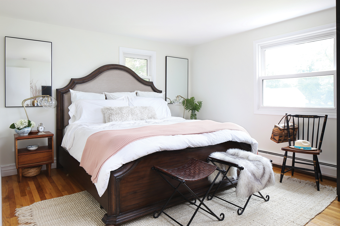 Master bedroom with a substantial dark wooden bed frame and white linens . 