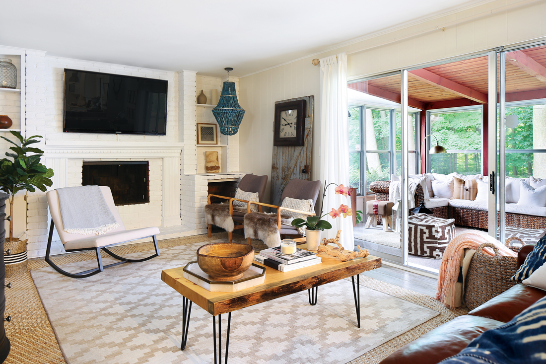 Living room with tons of seating options and a television mounted above the fireplace with a view out to the covered patio. 