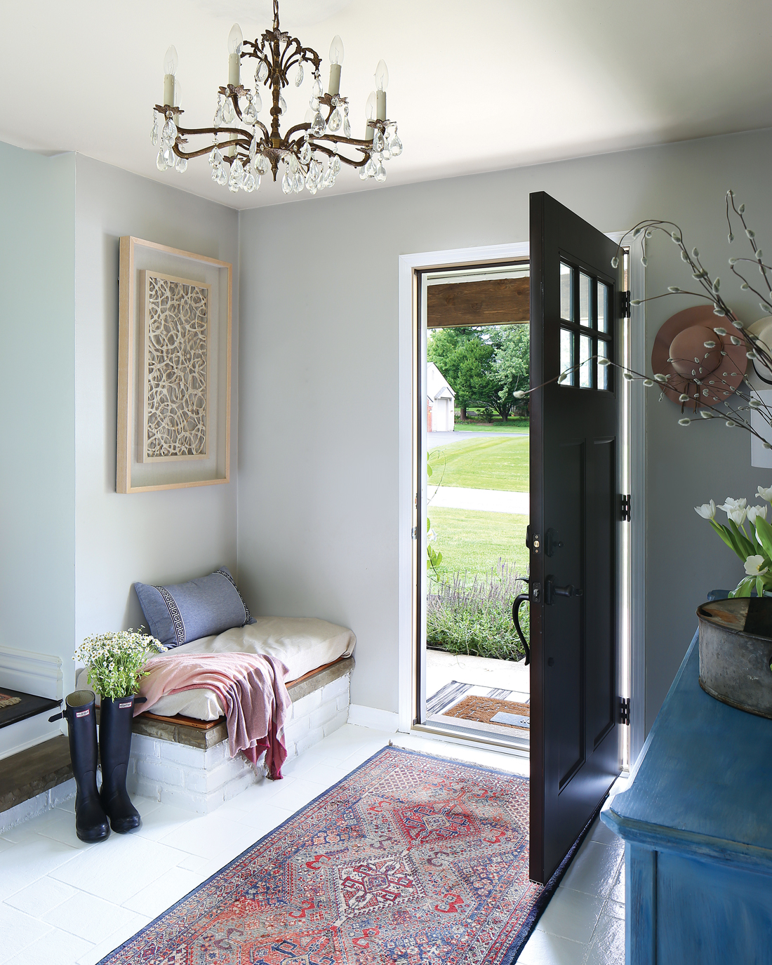 An entry way with a welcoming open door and a vintage Persian runner with an antique chandelier hanging from the ceiling. 