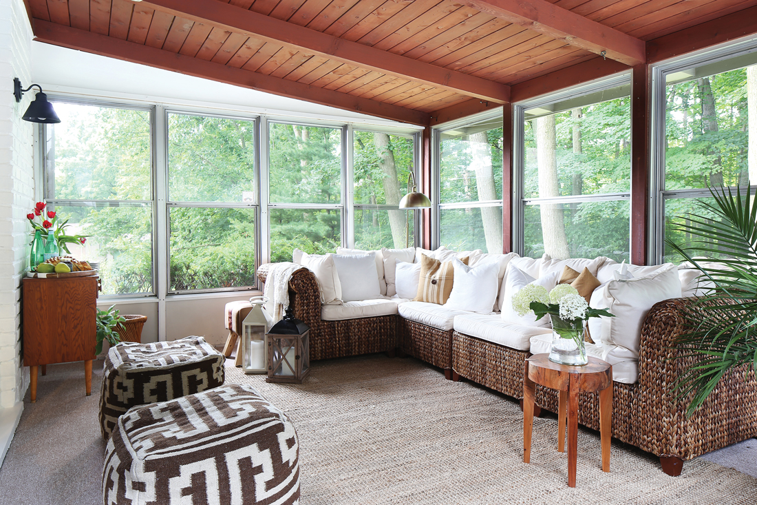 The sun porch overlooks stunning views of nature with a thatched whicker sectional and aztec inspired poofs for additional seating. 