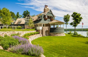 sprawling green grass leading up to a lakefront cottage.