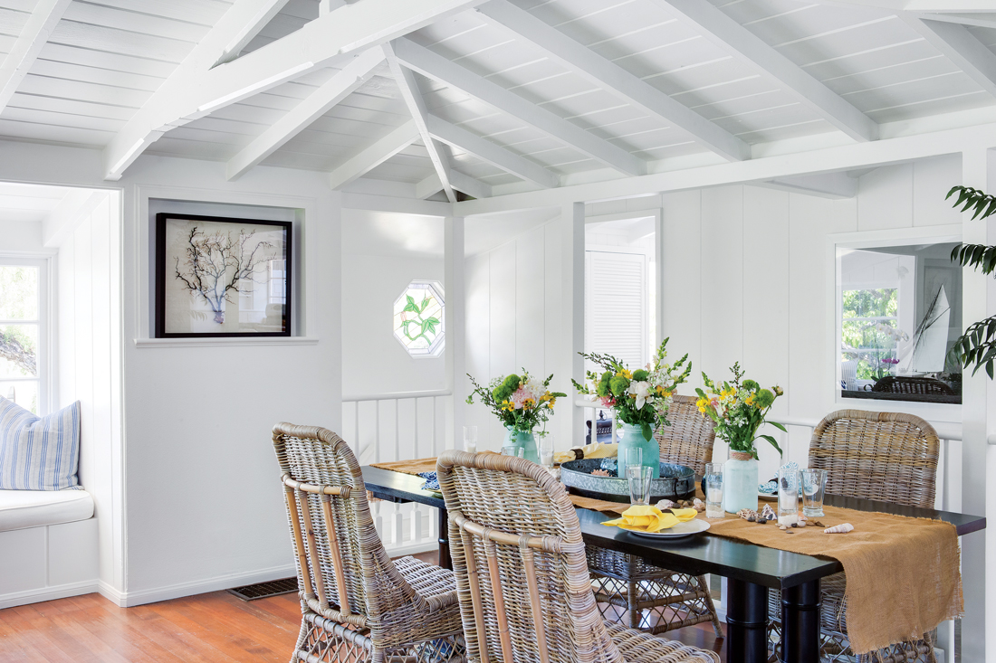 Wicker chairs with an antiqued white wash are a beautiful contrast with the clean lines of the black dining table