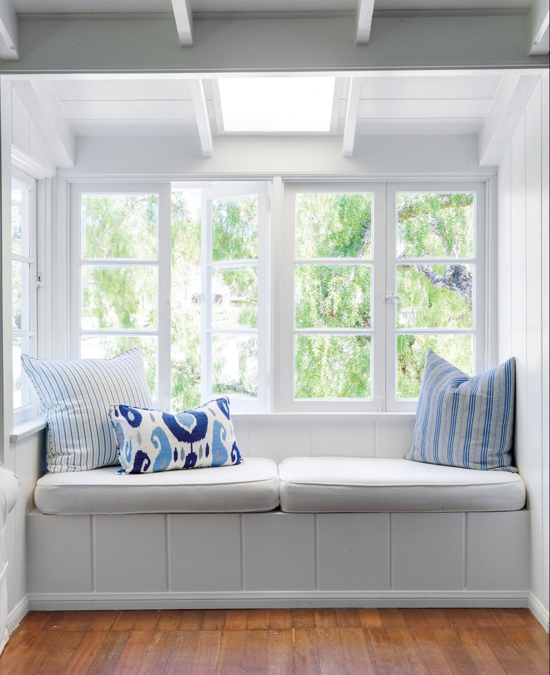 Window seat with all white walls and vaulted ceilings. 