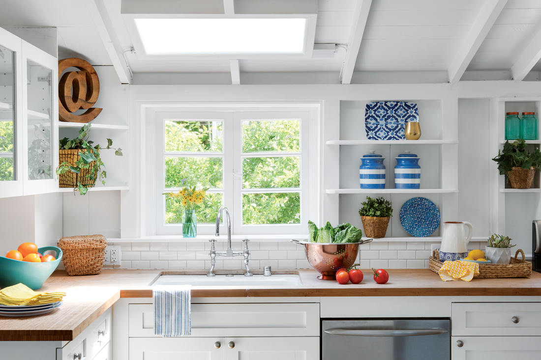 Light and bright kitchen with custom white exposed shelving and butcher block counter-top. 