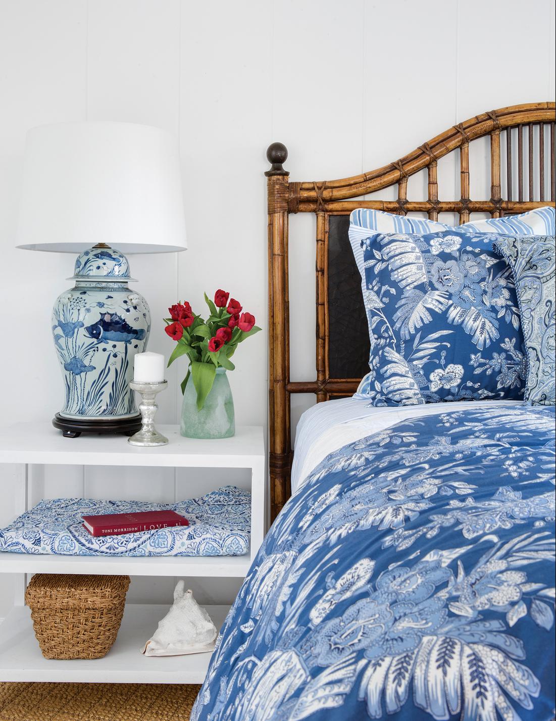 Bedroom with rattan headboard and blue and white accents on the bed and on the nightstand. 