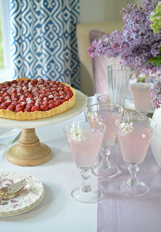 raspberry tart and pink lemonade on a pretty table with lilacs