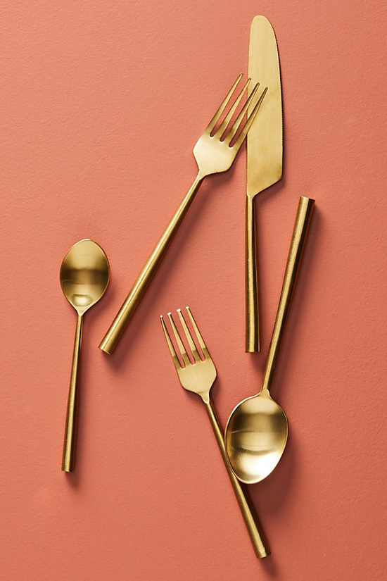 Coral colored backdrop featuring gold plated flatware